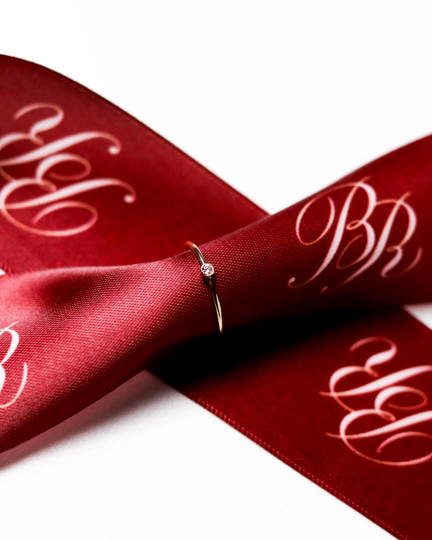 Delicate 14k gold filled ring with a cubic zirconia stone displayed on a red ribbon.